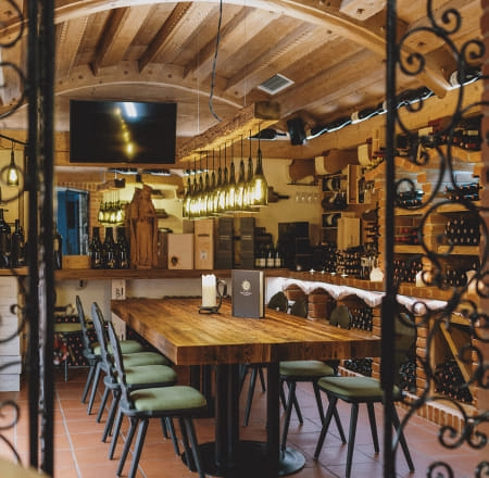 Gemütliche Weinlounge mit Holztisch und Regalen voller Wein.